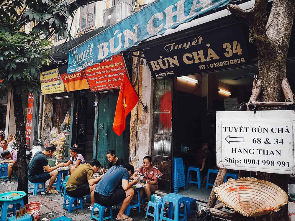 Tourists happily enjoy the rustic street food in hanoi
